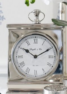 a silver clock sitting on top of a table