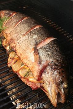 a fish is cooking on the grill with some herbs in it's back end