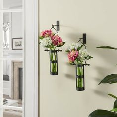 two vases with flowers are hanging on the wall