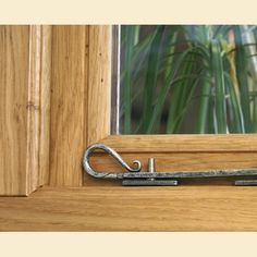 a close up of a metal door handle on a wooden window sill with grass in the background