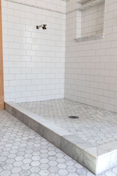 an empty bathroom with white tile and hexagonal floor tiles on the shower wall