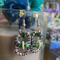 a pair of earrings sitting on top of a glass cup next to a blue flower