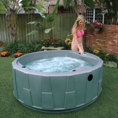 a woman sitting in the back yard next to a hot tub