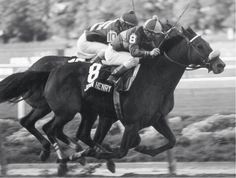 two jockeys are riding their horses on the track