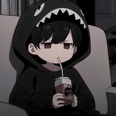 a person sitting on a couch with a drink in their hand and a shark hoodie