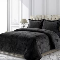 a black comforter set on a bed in a room with white walls and marble flooring