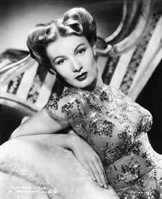 an old black and white photo of a woman in a dress sitting on a chair