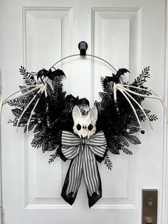 a wreath decorated with black and white ribbons, fake bats and a skull on the front door