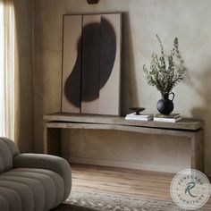 a living room with a couch, mirror and vase on the table in front of it