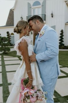 a bride and groom standing in front of a house