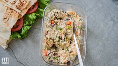 a salad in a plastic container with a fork next to it and a wrapper on the side