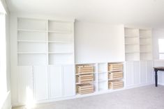 an empty room with white bookcases and drawers