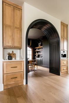 an arched doorway leads into a kitchen with wooden cabinets and counter tops, along with hardwood flooring