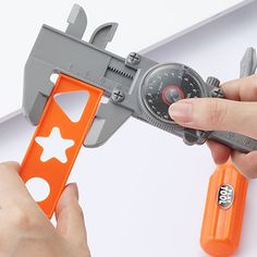 a person is holding an orange and gray calculator in front of a pair of scissors