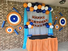 an orange and blue birthday party with balloons, streamers and eyeballs on the wall