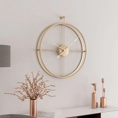 a clock on the wall above a table with vases and flowers in front of it