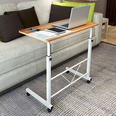 a laptop computer sitting on top of a wooden table next to a white couch in a living room