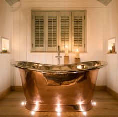 a bathroom with a large copper bathtub and candles