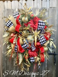 a christmas wreath hanging on the side of a wooden fence with red, white and gold decorations