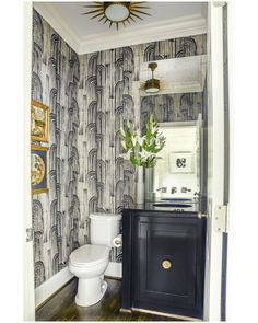 a white toilet sitting in a bathroom next to a black cabinet with flowers on it