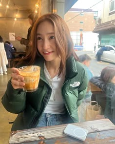 a woman sitting at a table with a drink in her hand