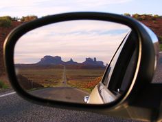 a car's rear view mirror is shown with mountains in the background