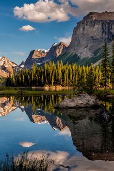 the mountains are reflected in the still water of this lake, with pine trees on both sides