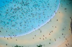 many people are swimming in the blue water and on the white sand beach with palm trees