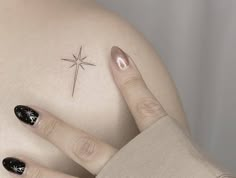 a woman's hand with black and white nail polish on her left side, next to a star tattoo