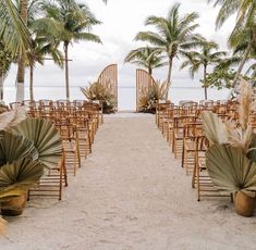 an outdoor ceremony set up on the beach with palm trees and chairs for guests to sit in