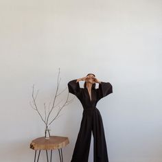 a woman standing in front of a white wall with her hands on her head and looking up