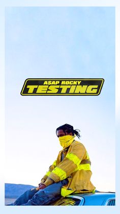 a woman sitting on top of a blue car under a yellow sticker that says testing