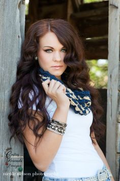 a beautiful young woman posing for a photo in front of a wooden structure with her hands on her hips