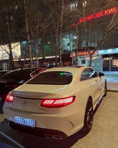 a white car parked in front of a building at night