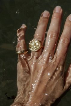 a person's hand with a ring on it in the water