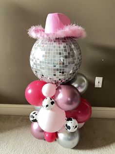 a bunch of balloons that are in the shape of a disco ball with a pink hat on top