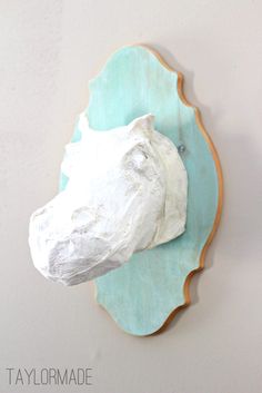 a white horse head mounted to the side of a wall with a blue plate on it