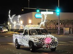 a truck decorated with christmas lights driving down the street