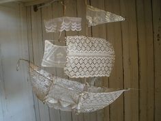 an umbrella made out of lace hanging from the ceiling in front of a wooden wall