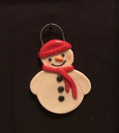 a ceramic snowman ornament with a red hat and scarf on it's head