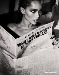 a woman reading a newspaper while laying in bed