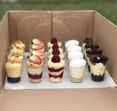 an open cardboard box filled with desserts on top of each other and topped with strawberries