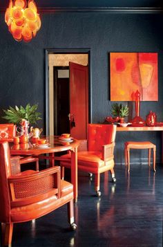 a dining room with orange chairs and paintings on the wall