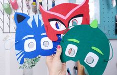 three masks are being held up in front of a wall full of crafting supplies