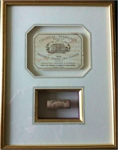 two framed corks are in a gold frame