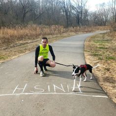 a man kneeling down on the side of a road with a dog attached to his leash