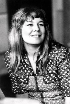 a woman sitting at a table in front of a window with her eyes closed and smiling