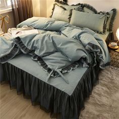 an unmade bed with ruffled blue sheets and pillow cases on top of it