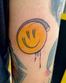 a yellow smiley face tattoo on the arm