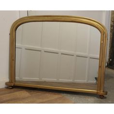 a large gold framed mirror sitting on top of a wooden floor next to a wall